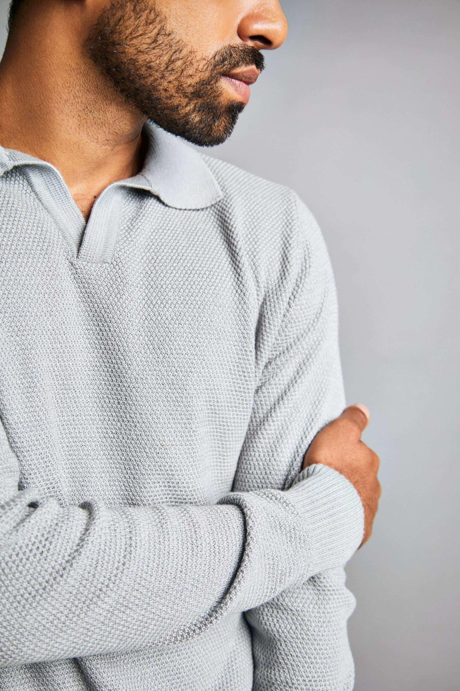 Hombre con suéter de punto gris claro, textura tejida, moda masculina elegante.